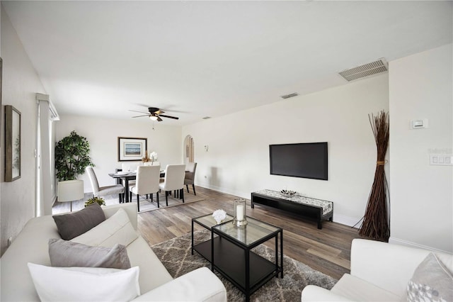 living room featuring ceiling fan and dark hardwood / wood-style floors