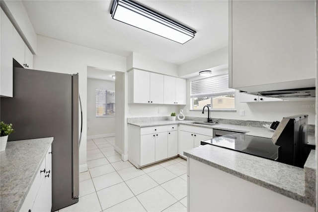 kitchen with stainless steel fridge, sink, light tile patterned floors, white cabinets, and range