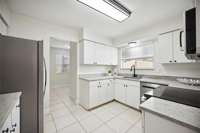 kitchen featuring appliances with stainless steel finishes, light tile patterned floors, white cabinetry, and sink