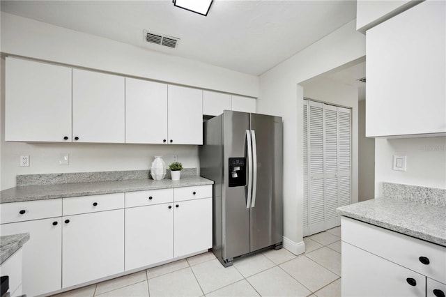 kitchen with white cabinets, stainless steel fridge, light stone counters, and light tile patterned floors