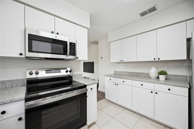 kitchen with white cabinets, appliances with stainless steel finishes, and light tile patterned floors