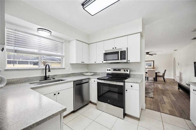 kitchen with stainless steel appliances, ceiling fan, sink, white cabinets, and light tile patterned flooring