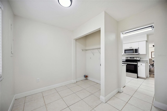 interior space with light tile patterned floors, white cabinets, and stainless steel electric range