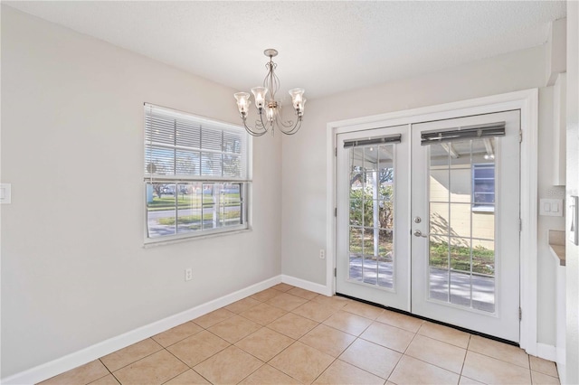 entryway featuring light tile patterned flooring, french doors, a textured ceiling, and an inviting chandelier