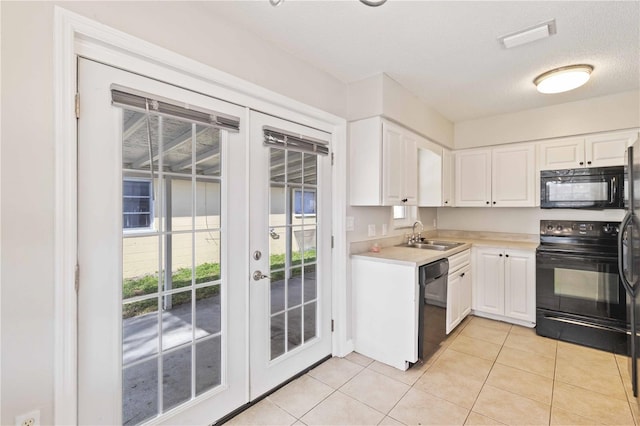 kitchen with french doors, sink, light tile patterned floors, white cabinets, and black appliances