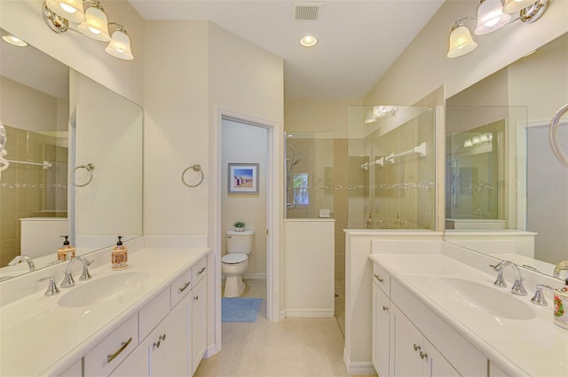 bathroom with tile patterned flooring, a tile shower, vanity, and toilet