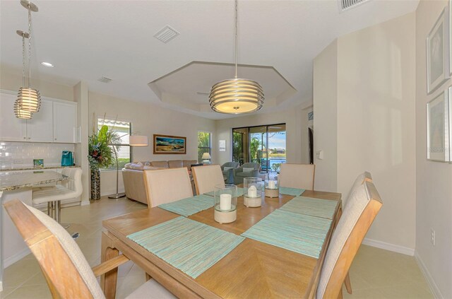 tiled dining area with a raised ceiling and a wealth of natural light