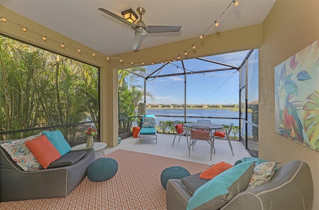 sunroom / solarium featuring ceiling fan and a water view