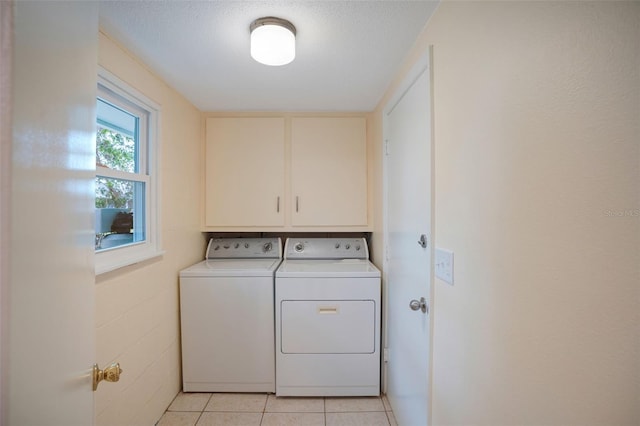 washroom featuring washer and clothes dryer, a textured ceiling, light tile patterned floors, and cabinets