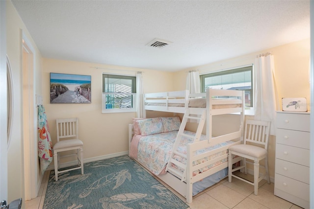 bedroom with a textured ceiling, multiple windows, and light tile patterned floors