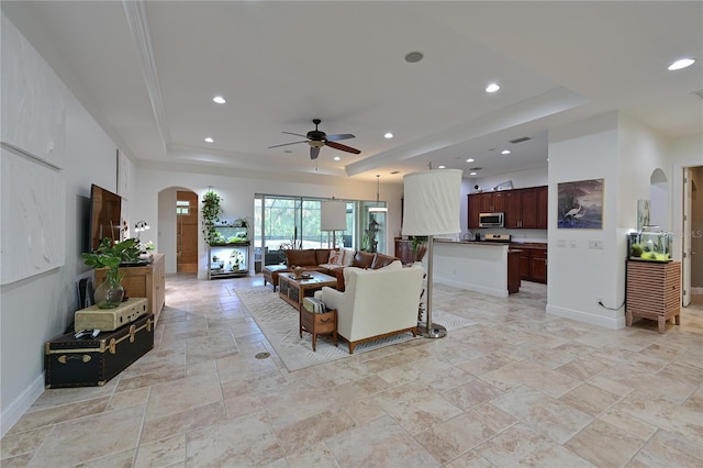 living room featuring a raised ceiling and ceiling fan