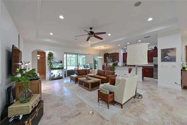 living room with a raised ceiling and ceiling fan