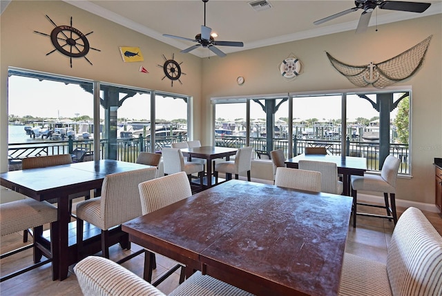 dining space featuring a water view, ceiling fan, and crown molding