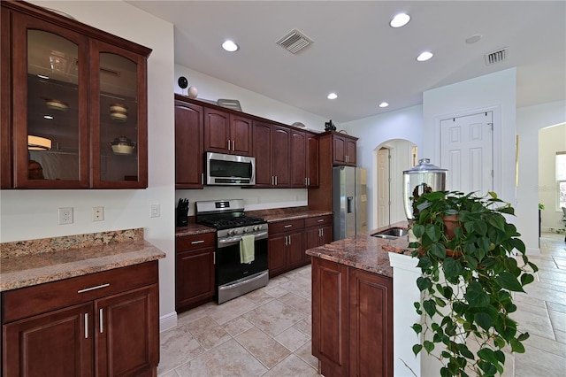 kitchen with dark stone countertops, dark brown cabinets, and appliances with stainless steel finishes