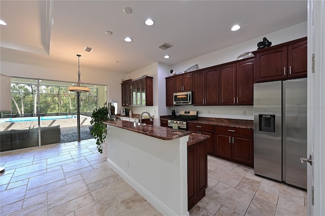 kitchen featuring appliances with stainless steel finishes, dark brown cabinetry, sink, decorative light fixtures, and dark stone countertops