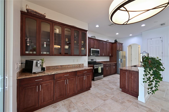 kitchen featuring light stone counters, dark brown cabinets, and stainless steel appliances