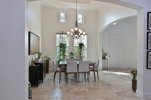 dining room featuring a notable chandelier, a towering ceiling, and crown molding