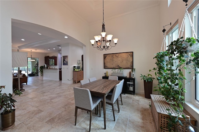 dining space featuring crown molding, a high ceiling, and an inviting chandelier