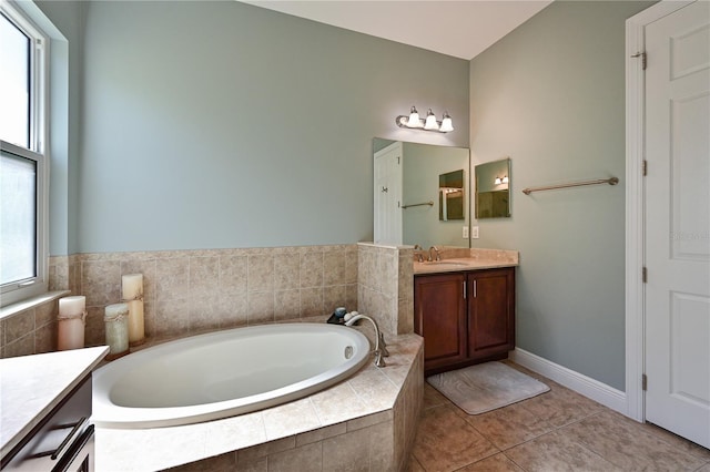 bathroom with tile patterned flooring, vanity, and a relaxing tiled tub