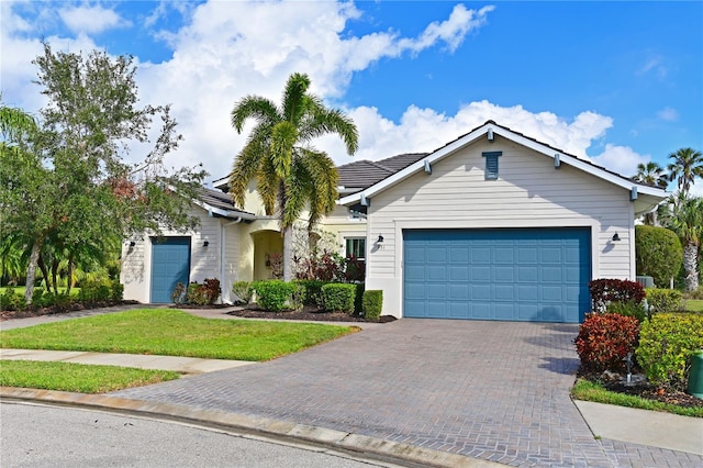 ranch-style house featuring a garage, a front lawn, and decorative driveway