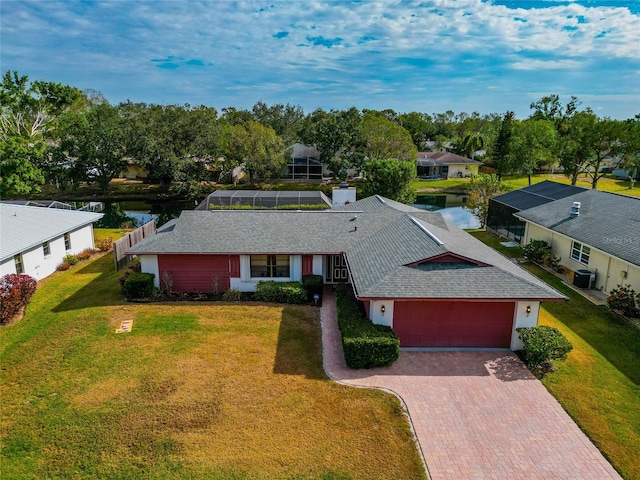 view of front of house featuring a water view, glass enclosure, a front lawn, and a garage