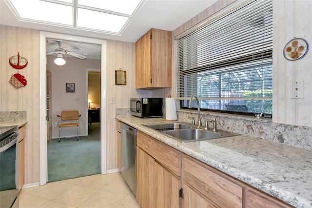 kitchen with wood walls, sink, ceiling fan, light colored carpet, and stainless steel appliances