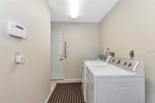 laundry area featuring washer and dryer, a textured ceiling, and light tile patterned flooring