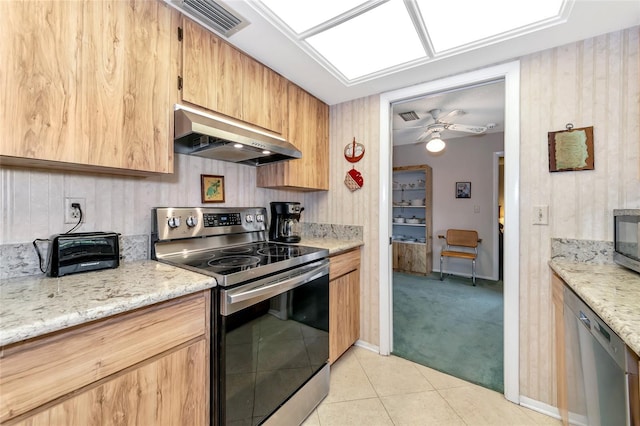 kitchen featuring exhaust hood, ceiling fan, light stone countertops, light colored carpet, and stainless steel appliances