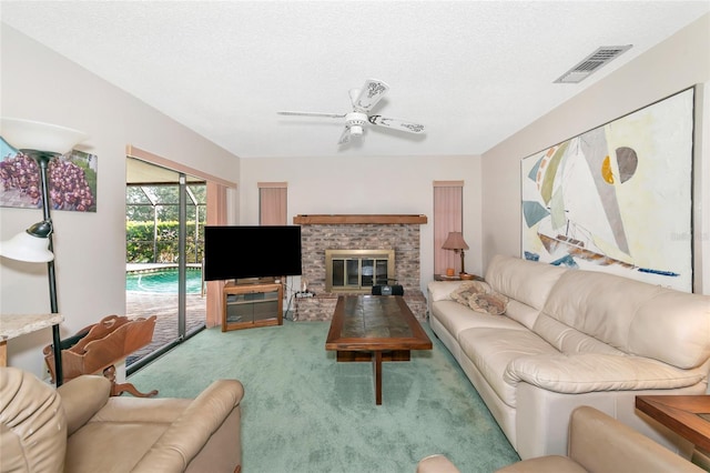 living room with carpet flooring, ceiling fan, a fireplace, and a textured ceiling