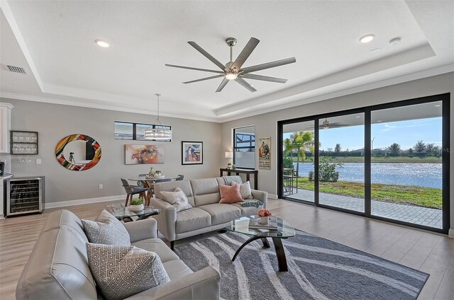 living room featuring hardwood / wood-style floors, a raised ceiling, a water view, wine cooler, and ceiling fan