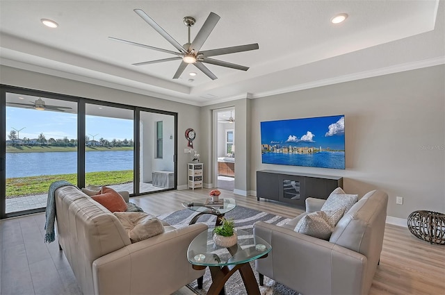 living room with ceiling fan, crown molding, light hardwood / wood-style flooring, and a tray ceiling