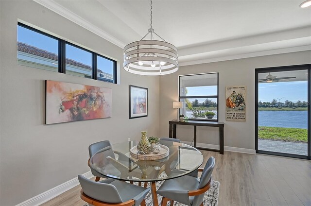 dining space with a wealth of natural light, light hardwood / wood-style flooring, a water view, and a notable chandelier