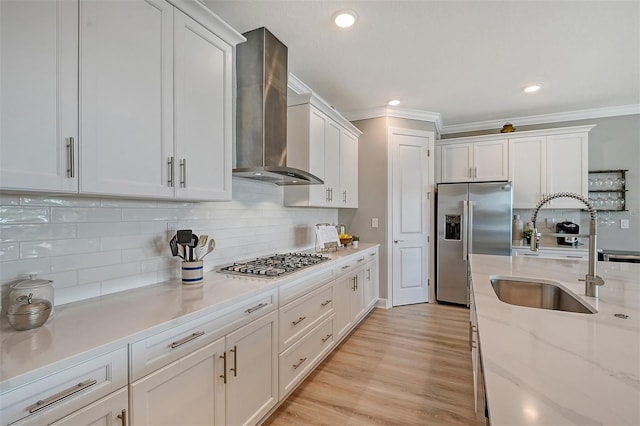 kitchen with backsplash, white cabinets, wall chimney range hood, sink, and appliances with stainless steel finishes