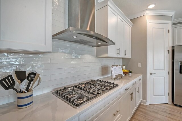 kitchen featuring backsplash, white cabinetry, wall chimney exhaust hood, and appliances with stainless steel finishes