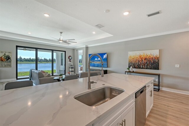 kitchen with stainless steel dishwasher, white cabinets, a water view, and light stone counters