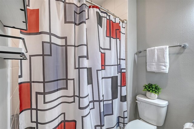 bathroom with toilet and curtained shower