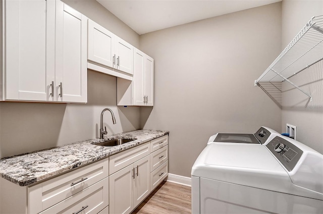 washroom featuring cabinets, light wood-type flooring, separate washer and dryer, and sink