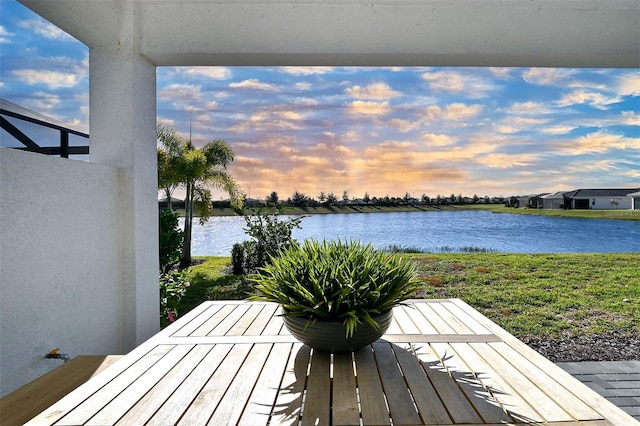 deck at dusk featuring a water view