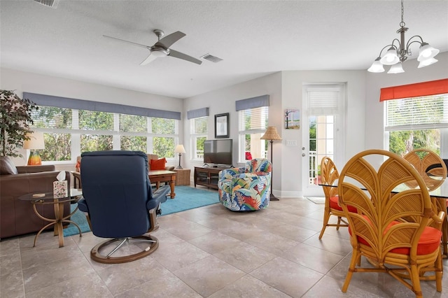 living room with ceiling fan with notable chandelier and a textured ceiling