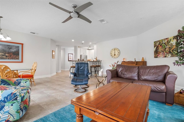 living room featuring a textured ceiling and ceiling fan with notable chandelier