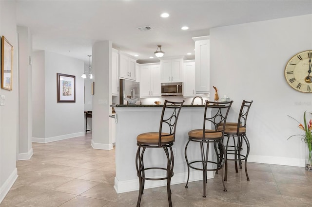 kitchen featuring white cabinetry, kitchen peninsula, stainless steel appliances, and a breakfast bar area