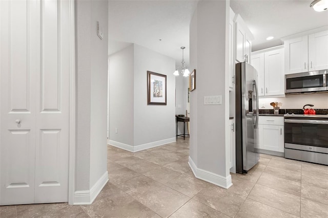 kitchen with white cabinets, decorative light fixtures, stainless steel appliances, and an inviting chandelier