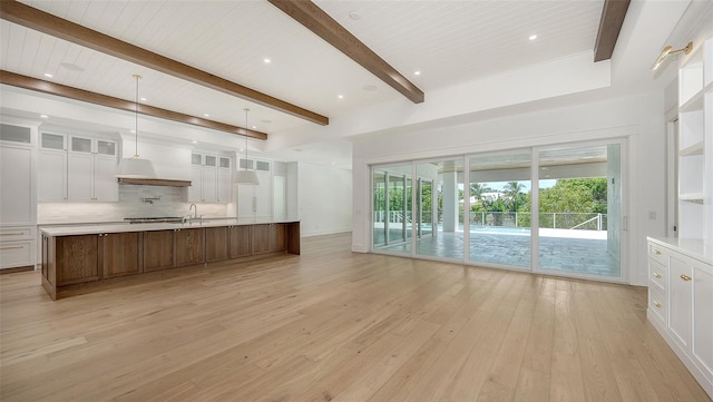 kitchen with beamed ceiling, a spacious island, white cabinetry, and wooden ceiling