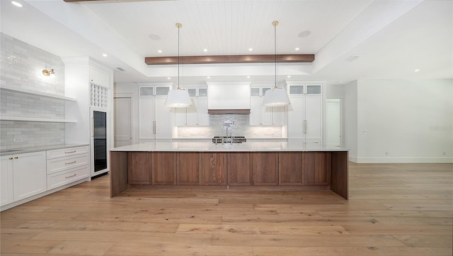 kitchen with white cabinetry, a spacious island, and custom range hood