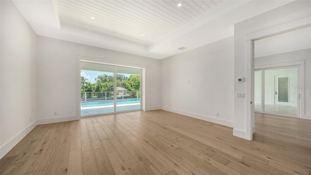 spare room featuring a raised ceiling, wooden ceiling, and light hardwood / wood-style flooring