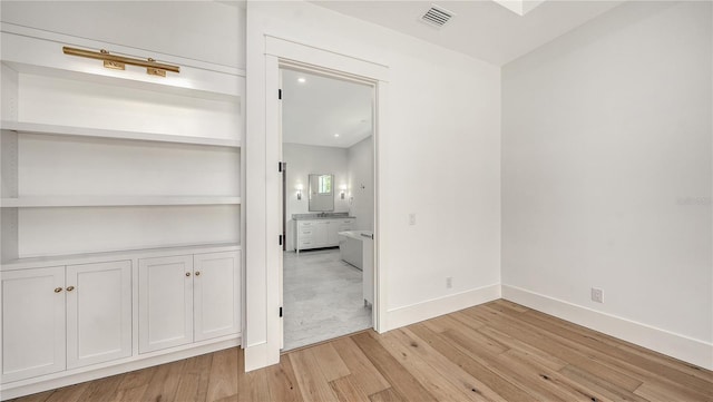 interior space with built in shelves and light hardwood / wood-style floors