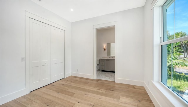 unfurnished bedroom with ensuite bath, sink, and light hardwood / wood-style floors