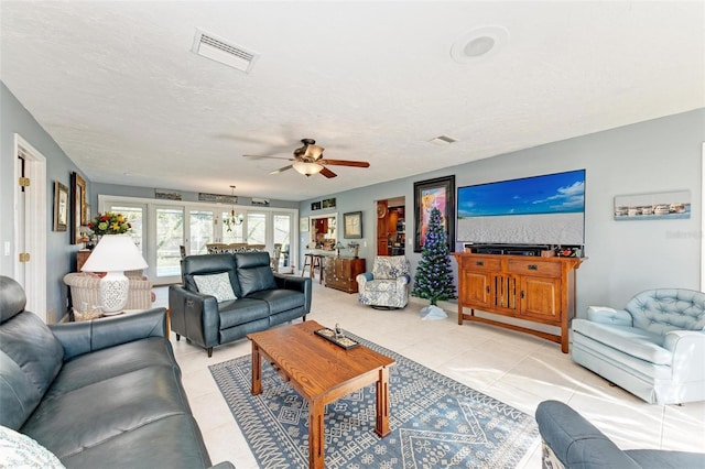 living room with light tile patterned flooring, ceiling fan, and a textured ceiling