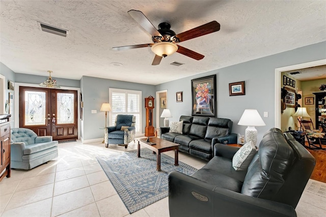 tiled living room featuring french doors, ceiling fan, and a textured ceiling