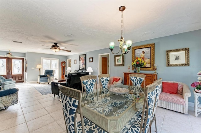 dining room with ceiling fan with notable chandelier, light tile patterned floors, and a textured ceiling